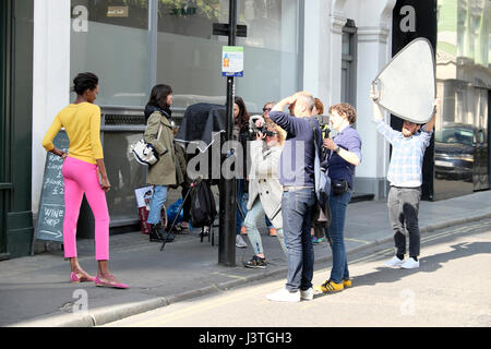 Troupe femmina fotografare Fotografo giovane nero moda modello in pantaloni rosa e giallo in alto nel becco Street, Soho, Londra W1 UK KATHY DEWITT Foto Stock