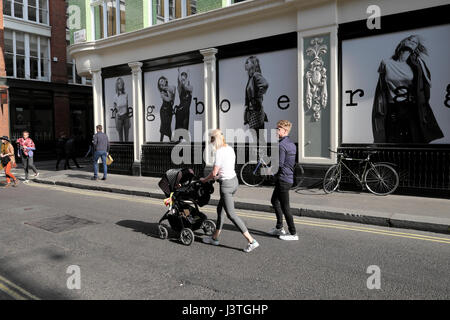 Coppia con un bambino la PRAM oltrepassando la "rag & bone' store boutique in Soho Londra UK KATHY DEWITT Foto Stock