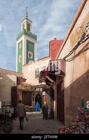 MEKNES, Marocco - 18 febbraio 2017: persone non identificate a piedi in strada di Meknes con vista di Bou Inania Madrasa minareto, Marocco. Foto Stock