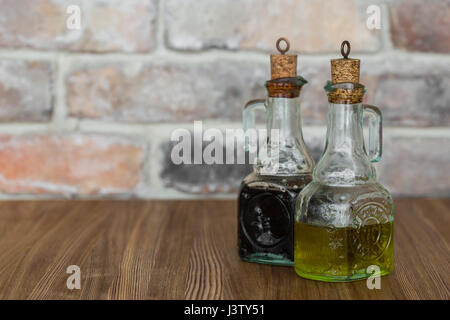 Olio e aceto balsamico di bottiglie di vetro con beccucci in mattone rustico sfondo a parete con spazio di copia Foto Stock