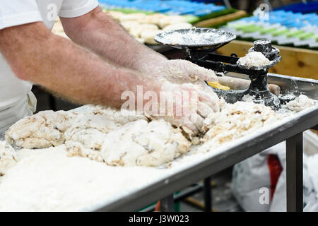 Un fornaio pesa di porzioni di impasto come egli rende soda irlandese focacce di pane. Foto Stock