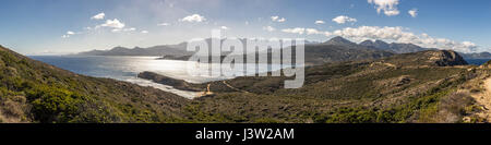 Vista panoramica attraverso la macchia della Revellata e Punta di l'Oscelluccia verso la cittadella di Calvi lungo la costa occidentale della Corsica con montagne innevate Foto Stock