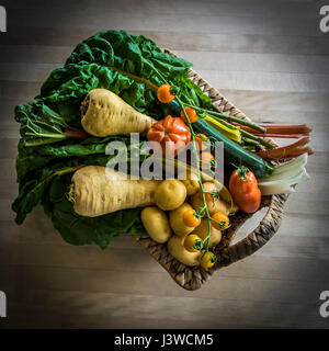 Un cestello di vari ortaggi freschi alimenti fonte di nutrizione Ingredienti Pomodori pastinaca patate Rainbow Chard ingredienti per la cottura Foto Stock