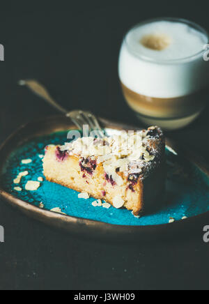 Pezzo di torta e un bicchiere di latte su sfondo scuro Foto Stock