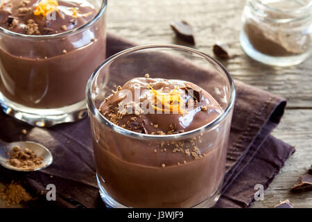 Mousse al cioccolato guarnita con scorza di arancia in bicchieri su sfondo in legno close up - deliziosa casa budino di cioccolato Foto Stock