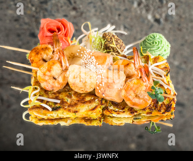Gamberetti spiedini di salmone su vegetali omelette su sfondo di calcestruzzo Foto Stock