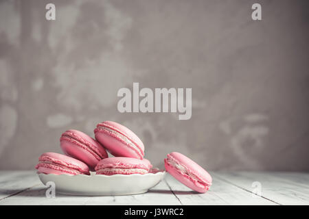 Lampone rosa pastello Macarons o amaretti su una lastra di cemento sullo sfondo di pietra Foto Stock