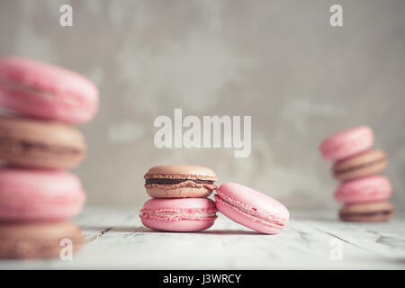 Pila di lampone e cioccolato color pastello Macarons o amaretti su calcestruzzo sfondo di pietra Foto Stock