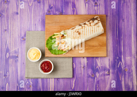 Shawarma di pollo e due bicchieri di bianco con ketchup e formaggio viola sul tavolo di legno Foto Stock