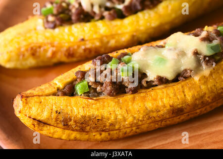 Cotta mature piantaggine farcite con carne macinata, oliva, peperone verde e cipolla, cosparso con formaggio Foto Stock