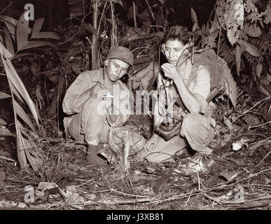 Codice Navajo talker a Bougainville nel dicembre 1943 durante la Seconda Guerra Mondiale. Caporale Henry cuocere Jr (sinistra) e privato di prima classe George H Kirk (destra), servendo con un segnale di Marino, unità di operare una radio portatile impostato in una radura di aver violato in la fitta giungla vicino dietro le linee anteriore. Foto Stock