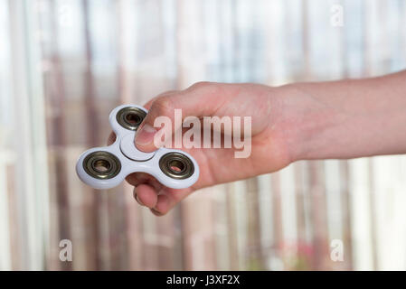 Giovane ragazzo giocando con agitano: spinner giocattolo per alleviare lo stress a casa Foto Stock