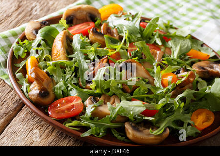 Pasto vegano: insalata di funghi fritti, rucola, pomodori ciliegia close-up su una piastra orizzontale. Foto Stock