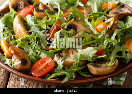 Vegetariano con insalata di funghi fritti, rucola, pomodori ciliegia close-up su una piastra orizzontale. Foto Stock