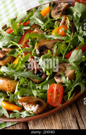 Insalata di funghi fritti, rucola, pomodori ciliegia close-up su una piastra verticale. Foto Stock