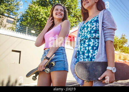 Due amiche, passeggiate all'aperto portando, skateboard, basso angolo di visione Foto Stock