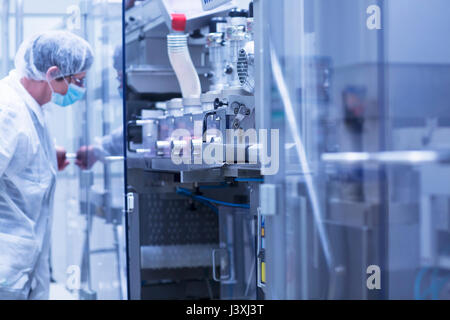 Lavoratore funzionamento di macchinari in stabilimento farmaceutico Foto Stock