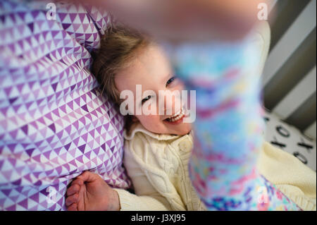 Ragazza ridere durante la riproduzione sul letto da giorno Foto Stock