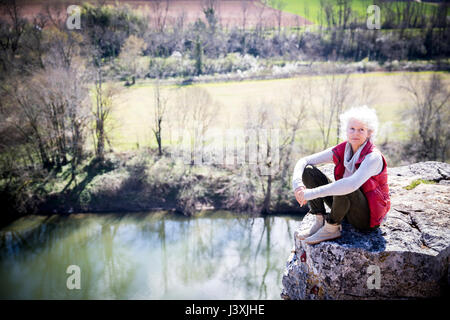 Donna seduta su roccia a guardare fotocamera a sorridere, Bruniquel, Francia Foto Stock
