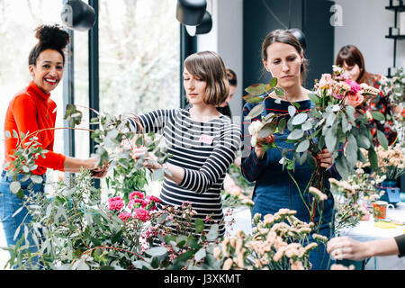 Fioraio studenti selezionando i fiori recisi a decorazione floreale workshop Foto Stock