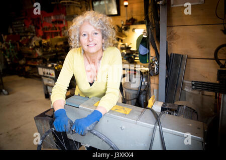 Ritratto di donna nel negozio di riparazione di biciclette Foto Stock