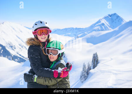 Ritratto di sci ragazza adolescente e fratello abbracciando nelle Alpi svizzere, Gstaad, Svizzera Foto Stock