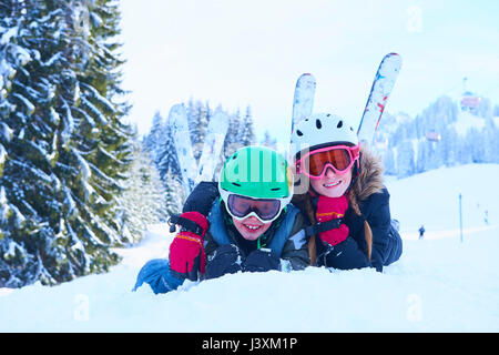 Ritratto di sci ragazza adolescente e fratello giacente nella neve Gstaad, Svizzera Foto Stock