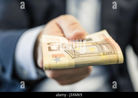 Close up di imprenditore il lato trasmissione piegato cinquanta le banconote in euro Foto Stock