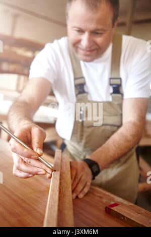 Falegname maschio marcatura legno con la matita sul banco di lavoro Foto Stock