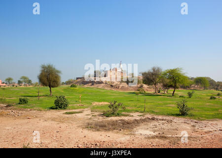 Un tempio indù in cima bhatner fort hanumangarh Rajasthan in India con erba di alberi di acacia e di restauro sotto un cielo blu chiaro in springtim Foto Stock