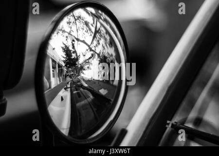 Strada di città relected su uno specchio auto. Foto in bianco e nero. Foto Stock