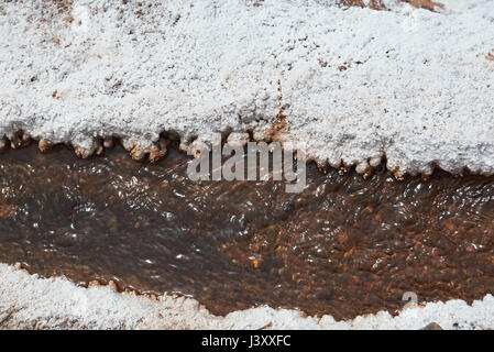 Close-up di acqua salata in esecuzione nel canale con sale bianco boarder Foto Stock