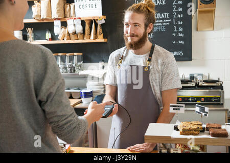 Il cliente il pagamento senza contatto in un Cafè presso il contatore Foto Stock