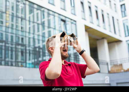 Funny Man utilizzando cartone la realtà virtuale goggle all'aperto Foto Stock