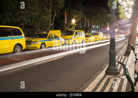 Striature di vetture passando giallo taxi in corrispondenza di una stazione di taxi, Funchal, Madeira Foto Stock