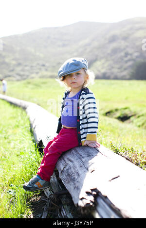 Ritratto di bimbi maschio nel tappo piatto seduti sul log Foto Stock