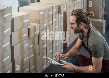 Uomo con tavoletta digitale per controllare boxed prodotti in fabbrica e magazzino Foto Stock