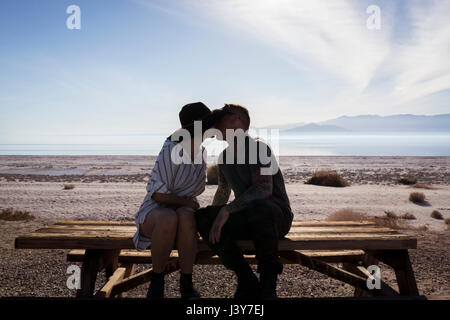 Coppia seduta sul banco di picnic kissing, Salton Sea, CALIFORNIA, STATI UNITI D'AMERICA Foto Stock