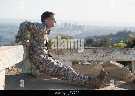 Soldato indossando indumenti di combattimento facendo retromarcia push up, Runyon Canyon, Los Angeles, California, Stati Uniti d'America Foto Stock