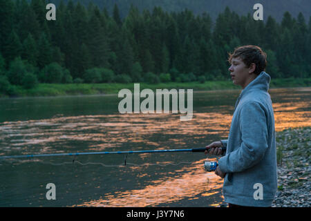 Ragazzo adolescente la pesca in fiume al tramonto, Washington, Stati Uniti d'America Foto Stock