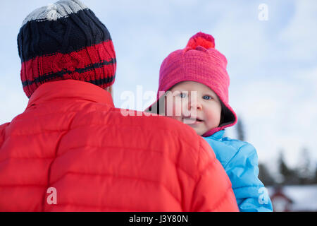 Padre che trasportano giovane figlio di paesaggi innevati Foto Stock