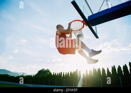 Giovane uomo di salto e facendo un fantastico Slam Dunk giocando stree Foto Stock