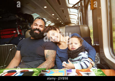 Moderno e giovane famiglia viaggi in treno. Sorridendo felice famiglia in viaggio Foto Stock