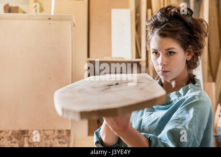 Giovane donna esame campione di legno in un workshop Foto Stock