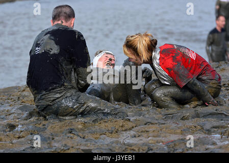 I concorrenti della MAD Maldon Mud Race hanno coperto di fango dalle corse attraverso e attraverso il fiume Blackwater nell'Essex, Regno Unito Foto Stock