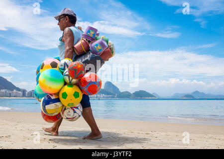 RIO DE JANEIRO - Febbraio 10, 2017: Brasiliano beach venditore passeggiate lungo la spiaggia di Copacabana in cerca di clienti per il suo magazzino delle colorate sfere Foto Stock