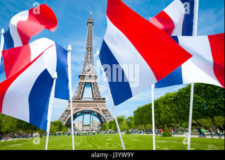 Tricolore francese bandiere che sventolano nel cielo blu su una luminosa giornata di primavera di fronte alla Torre Eiffel a Parigi, Francia Foto Stock