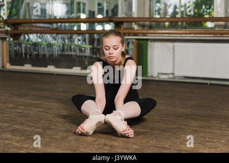 Giovane bella ballerina in fase di riscaldamento nella classe di balletto. Bellissima ballerina facendo esercizi di stretching in classe di balletto Foto Stock