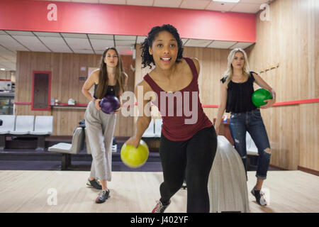 Una giovane donna bowling con gli amici. Foto Stock