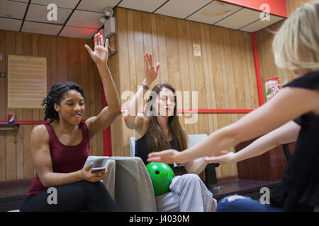 Tre giovani donne il tifo a una pista da bowling. Foto Stock